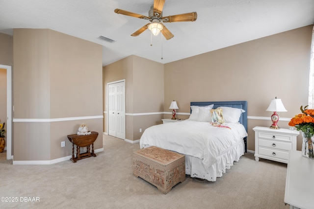 bedroom with light colored carpet, ceiling fan, and a closet