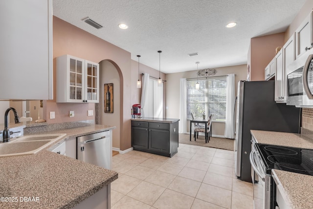 kitchen featuring hanging light fixtures, a textured ceiling, stainless steel appliances, and white cabinets