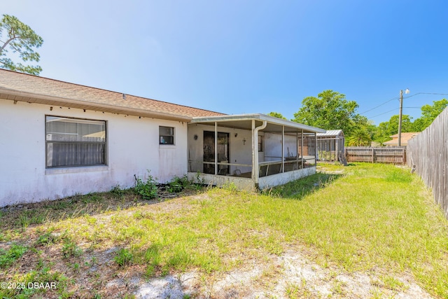 back of property featuring a fenced backyard, a sunroom, a yard, and stucco siding