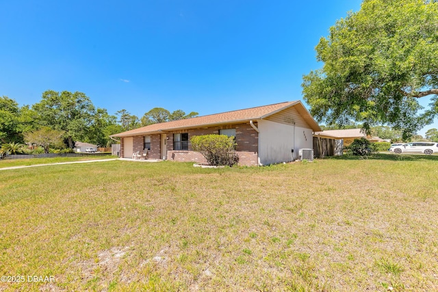 ranch-style home with brick siding, cooling unit, and a front lawn