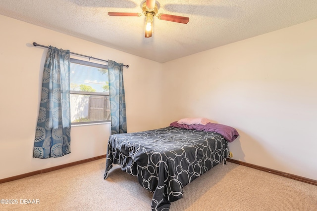 carpeted bedroom with a ceiling fan, baseboards, and a textured ceiling