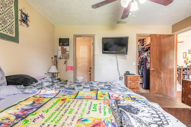 bedroom with a textured ceiling, a closet, connected bathroom, ceiling fan, and visible vents