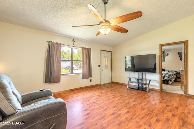 living room with ceiling fan, lofted ceiling, wood finished floors, and a textured ceiling