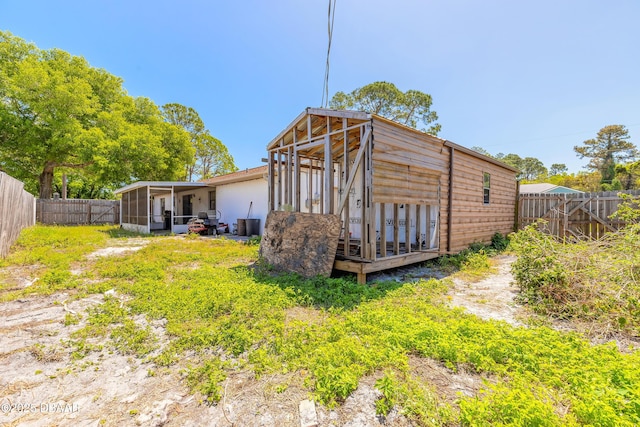 rear view of house featuring a fenced backyard and a sunroom
