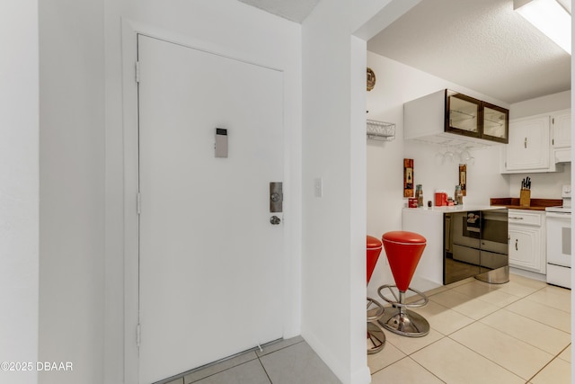 kitchen featuring white cabinetry, light tile patterned floors, white electric range, and a textured ceiling