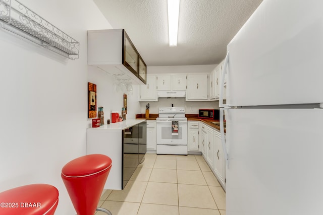 kitchen with a textured ceiling, light tile patterned floors, white cabinets, and white appliances