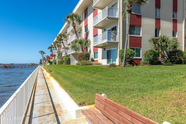 view of property's community with a water view and a lawn