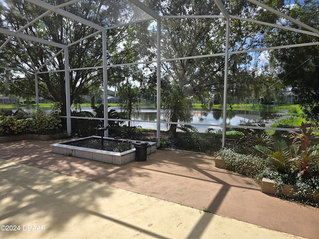 view of patio featuring a lanai and a water view