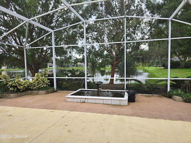 view of patio with glass enclosure and a water view