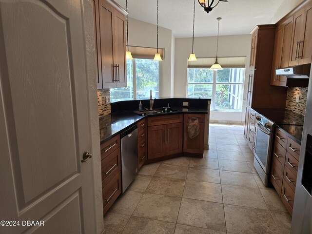 kitchen featuring hanging light fixtures, kitchen peninsula, light wood-type flooring, ceiling fan with notable chandelier, and appliances with stainless steel finishes