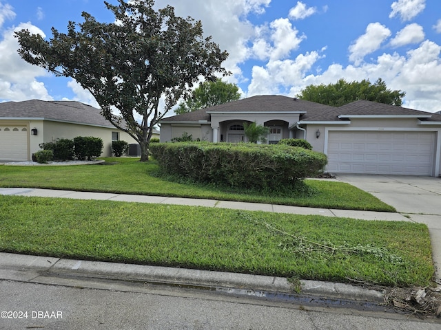 single story home featuring a garage and a front lawn