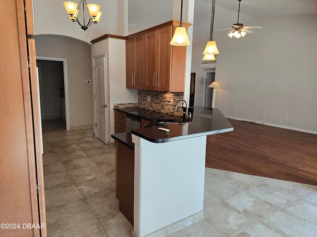 kitchen featuring sink, backsplash, kitchen peninsula, decorative light fixtures, and light wood-type flooring