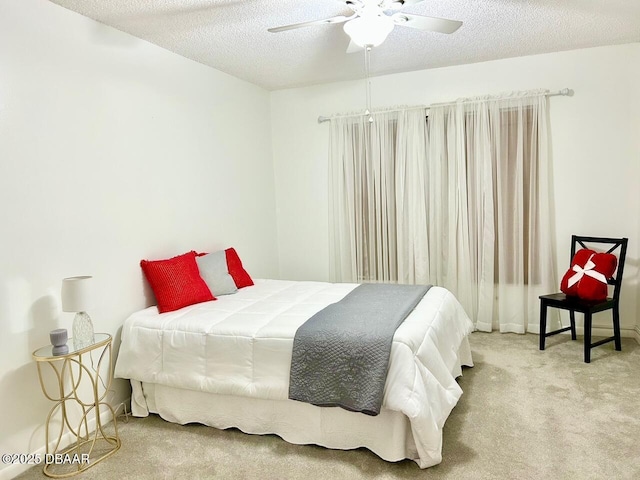 bedroom with ceiling fan, light carpet, and a textured ceiling