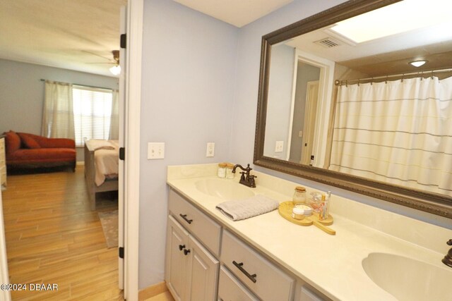 bathroom with hardwood / wood-style floors, ceiling fan, and vanity