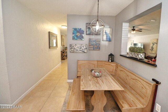 tiled dining room featuring ceiling fan with notable chandelier