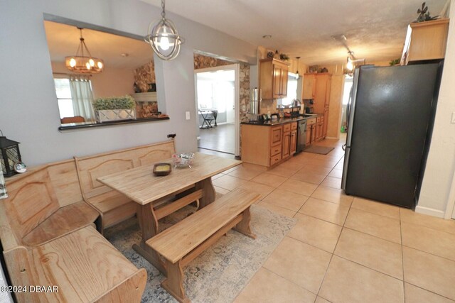 tiled dining area featuring a wealth of natural light, a notable chandelier, and sink