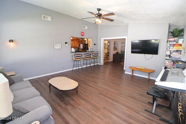 living room with dark hardwood / wood-style flooring, ceiling fan, and vaulted ceiling