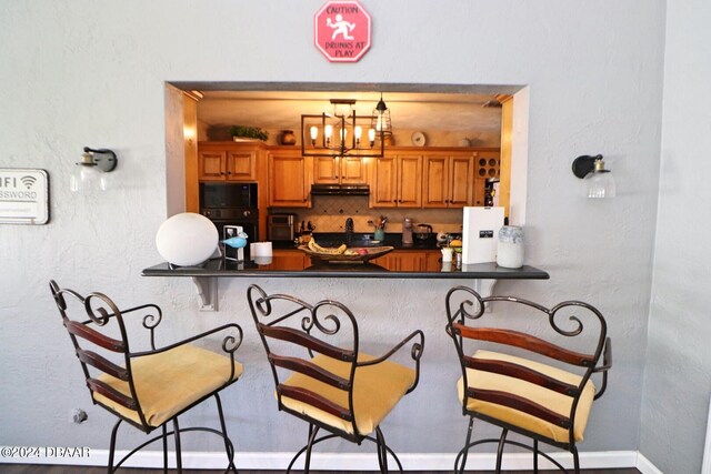 kitchen featuring kitchen peninsula, white fridge with ice dispenser, and a breakfast bar