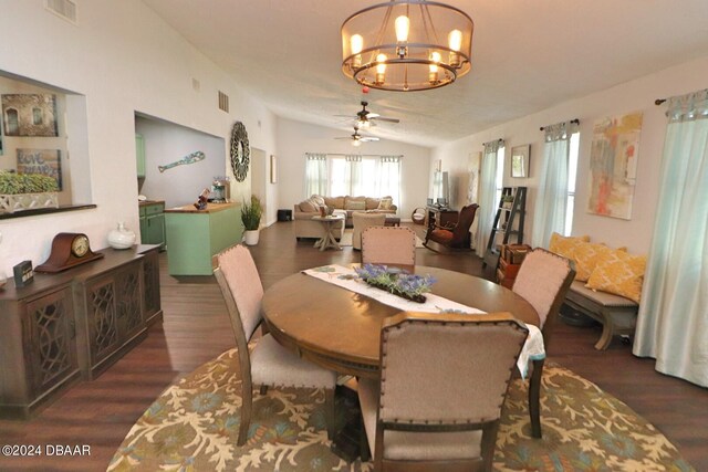 dining area with dark wood-type flooring, ceiling fan with notable chandelier, and vaulted ceiling