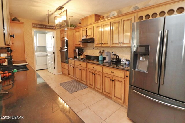 kitchen with black appliances, light tile patterned floors, a notable chandelier, washer / clothes dryer, and decorative backsplash