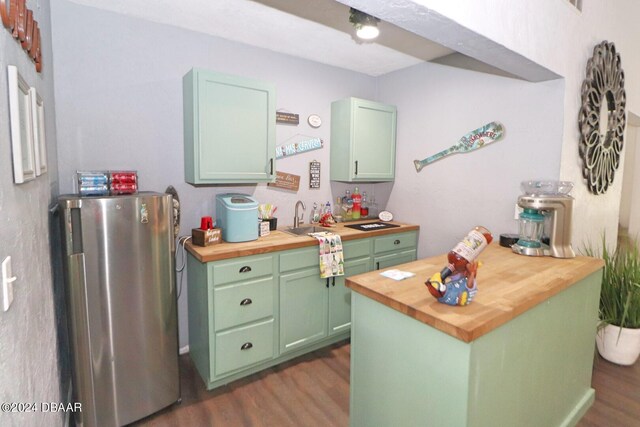 kitchen featuring green cabinets, butcher block countertops, dark wood-type flooring, and fridge