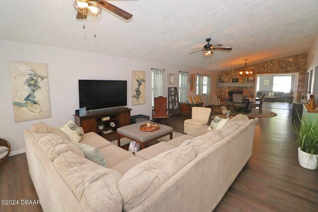 living room featuring dark wood-type flooring, ceiling fan with notable chandelier, and vaulted ceiling