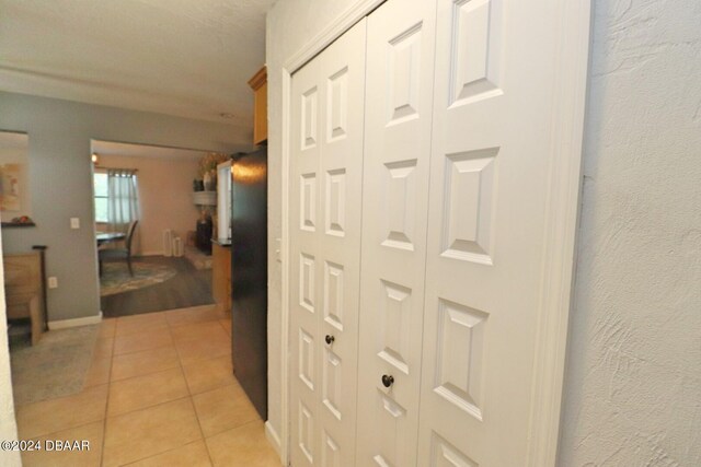 hall with a textured ceiling and light tile patterned floors