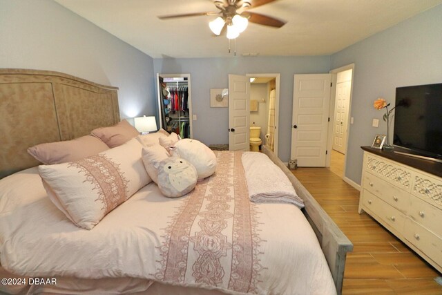 bedroom featuring a closet, a spacious closet, light hardwood / wood-style flooring, ceiling fan, and ensuite bathroom