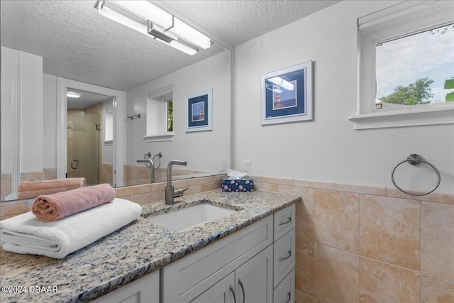 110 Ocean Way Dr, Ponce Inlet, FL 32127 - bathroom with a textured ceiling, vanity, a stall shower, tile walls, and healthy amount of natural light