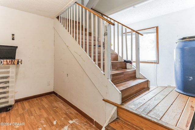 stairs with hardwood / wood-style floors and a textured ceiling