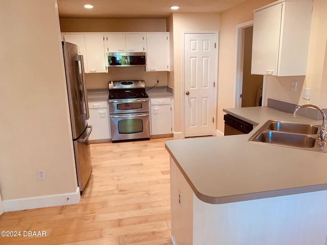 kitchen with stainless steel appliances, white cabinetry, sink, kitchen peninsula, and light wood-type flooring