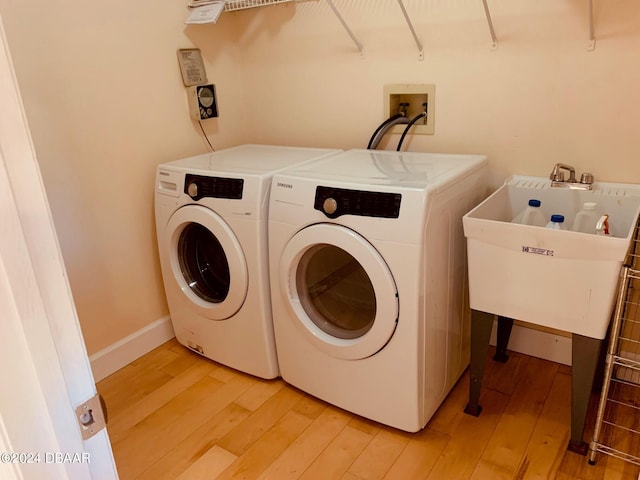 clothes washing area featuring light wood-type flooring and washing machine and clothes dryer