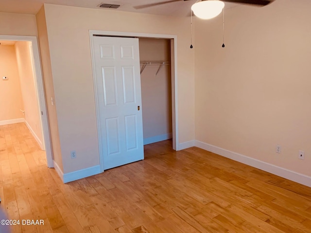 unfurnished bedroom featuring light wood-type flooring, ceiling fan, and a closet