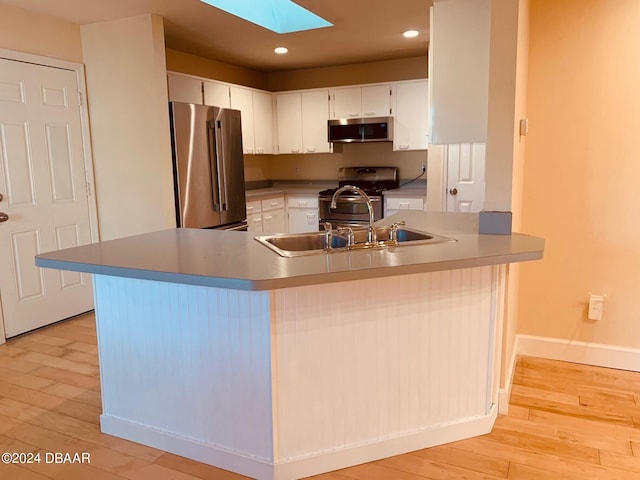 kitchen with kitchen peninsula, white cabinetry, light wood-type flooring, and appliances with stainless steel finishes