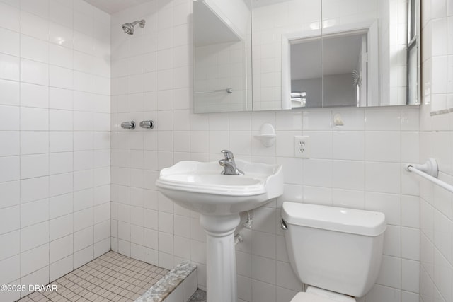 bathroom with tiled shower, tile walls, and toilet