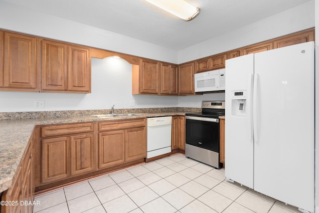 kitchen featuring white appliances, sink, a textured ceiling, and light tile patterned floors