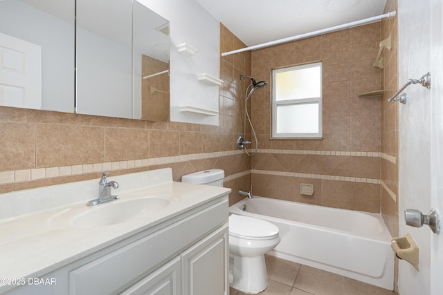 full bathroom with toilet, tile walls, vanity, tiled shower / bath combo, and tile patterned flooring