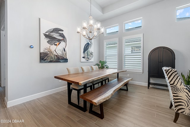 dining room featuring a towering ceiling, light hardwood / wood-style flooring, and an inviting chandelier