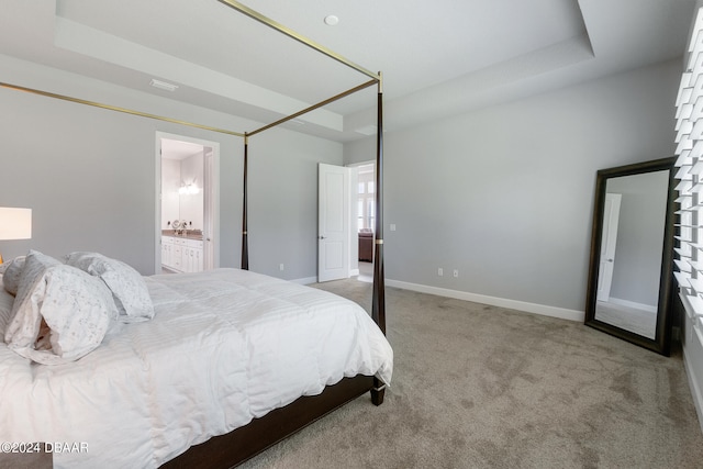 bedroom with light carpet, a raised ceiling, and connected bathroom