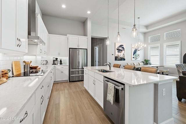 kitchen featuring white cabinets, wall chimney exhaust hood, sink, a kitchen island with sink, and appliances with stainless steel finishes