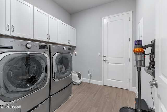 clothes washing area with cabinets, light hardwood / wood-style floors, and independent washer and dryer