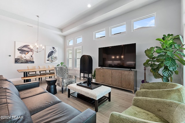 living room featuring light wood-type flooring, a chandelier, and a high ceiling