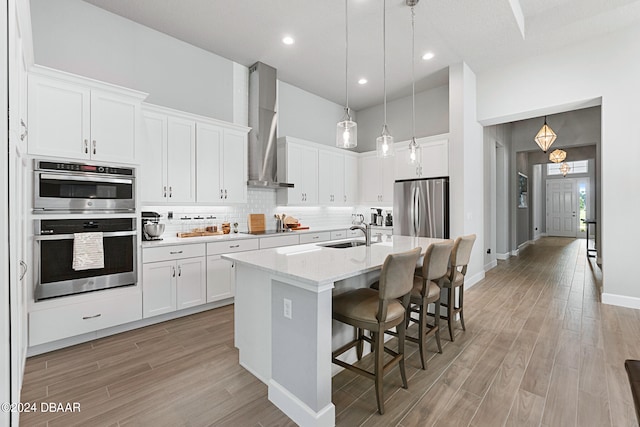 kitchen featuring a kitchen island with sink, appliances with stainless steel finishes, and white cabinets