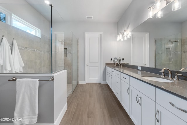 bathroom with tiled shower, hardwood / wood-style flooring, and vanity