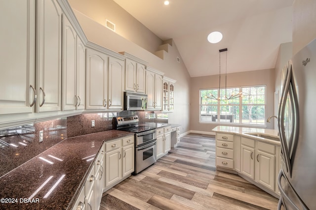 kitchen featuring stainless steel appliances, sink, light wood-type flooring, pendant lighting, and vaulted ceiling