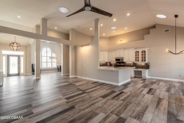 kitchen featuring high vaulted ceiling, pendant lighting, hardwood / wood-style floors, and white cabinets