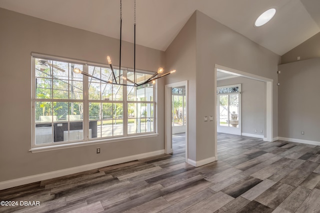 unfurnished dining area featuring high vaulted ceiling, a chandelier, and hardwood / wood-style floors