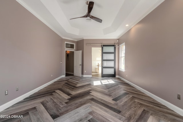 unfurnished bedroom featuring parquet flooring, ornamental molding, ceiling fan, a raised ceiling, and a barn door