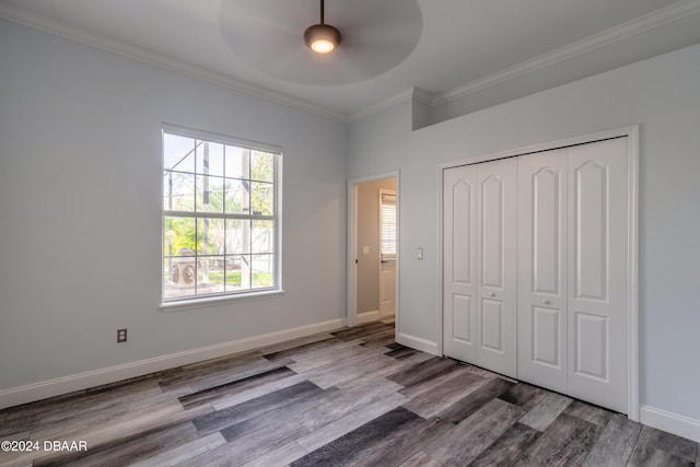 unfurnished bedroom featuring ornamental molding, wood-type flooring, ceiling fan, and a closet