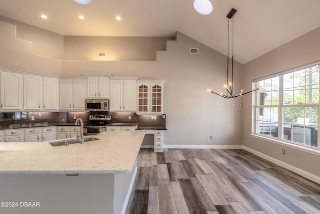 kitchen featuring stainless steel appliances, wood-type flooring, sink, high vaulted ceiling, and decorative light fixtures